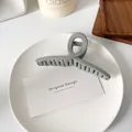 Eleganter mattgrauer Haarklammer für dickes Haar auf einem minimalistischen Tablett - Hellgrau