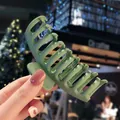 Large matte sage green hair claw clip for women shown in a stylish outdoor setting - Green