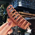 Matte orange-brown large hair claw clip for women held by hand in a cozy cafe setting - Orange