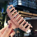 Matte pink large claw clip for thick hair held by hand in a soft outdoor setting - Khaki