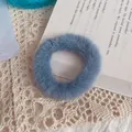 Soft faux rabbit fur scrunchie in misty blue color on a vintage aesthetic book background - Lake Blue