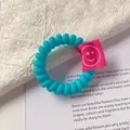 Elastico per capelli a spirale blu con etichetta quadrata rosa e faccina sorridente - Celeste