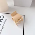 Minimalistische matt-cremefarbene Haarklammer für hohe Pferdeschwänze auf weißem Grund - Hellgelb