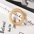Matte champagne spiral telephone cord hair tie on minimalist book aesthetic - Khaki