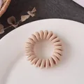 Elastic beige fabric-wrapped spiral hair tie in a minimalist ceramic dish setting - Khaki