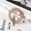 Matte champagne spiral telephone cord hair tie on minimalist book background - Light Gray