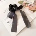 Elegant black organza hair scrunchie with long ribbon bow on aesthetic magazine background - Black