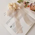 Elegant beige organza oversized bow scrunchie with long ribbons on a lifestyle background - Off White