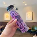 Elastic hair ties in purple candy colors inside a clear plastic jar with black lid - Purple