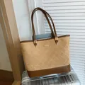 Bruine patchwork tote bag met gouden hardware op een zilverkleurige koffer - Khaki