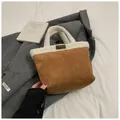 Stijlvolle bruine suède emmertas met witte lamswol afwerking en modieus label detail - Bruin