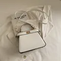 Elegante bolso trapecio blanco con borde negro y cierre giratorio dorado - Blanco