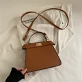 Elegante bolso trapezoidal de cuero caramelo con cierre giratorio dorado y bandolera - Marrón