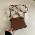 Braune trapezförmige Handtasche aus mattem Leder mit goldenem Drehverschluss und Schultergurt - Braun