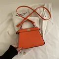 Minimalistische orangefarbene Trapez-Handtasche mit Metallverschluss und Gurt - Orange