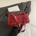 Dunkelrote Leder-Unterarmtasche mit Gürtelschnalle auf grauem Blazer Hintergrund - Rot