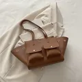 Braune Shopper-Tasche aus strukturiertem Leder mit Fronttaschen auf beigem Sakko - Braun