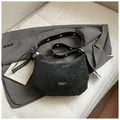 Detail of black semi-circle crossbody bag with silver eyelets and rustic finish - With Pendant / Black
