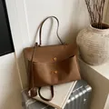 Brown textured suede tote bag with dual gold locks and top handle on a metal case - Brown