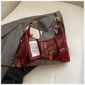 Dettaglio borsa sottobraccio in pelle cerata bordeaux con fibbie metalliche dorate - Rosso