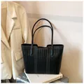 Close-up of black woven tote bag with white contrast stitching on a travel suitcase - No Pendant / Black