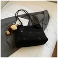 Detail of black suede hobo bag with floral laser-cut patterns and a plush bear charm - Black With Pendant
