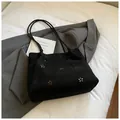 Close-up of laser-cut floral patterns on black suede tote bag with slim straps - Black without Pendant