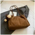Detail of laser-cut flower patterns on a dark brown suede hobo bag with a plush bear charm - Brown with Pendant