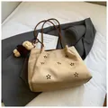 Detail of hollowed flower pattern on apricot suede shoulder bag with a bear charm - Khaki With Pendant