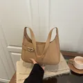 Elegante bolso baguette de cuero camello con hebilla dorada sobre bufanda de punto - Caqui