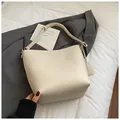 Détail du sac seau en cuir grainé blanc crème sur un costume gris pour un look chic - Blanc