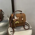 Brown frosted mini backpack with cartoon bear graphic and fuzzy charm on white table - Without Pendant / Brown