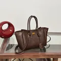 Deep brown tote bag with wing shape design and gold logo on wooden glass table - Toffee Brown