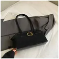 Close-up of black textured shoulder bag with gold metal buckle on grey suit fabric - No Pendant / Black