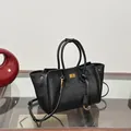 Black leather tote bag with gold metal logo and detachable shoulder strap in a minimalist style - Black