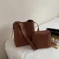 Conjunto de bolso cubo marrón con textura de lichi y neceser en cama blanca suave - Estilo Bolso Cubo Y Neceser / Marrón