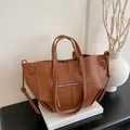 Braune Shopper-Tasche aus Leder mit Kontrastnähten in minimalistischem Ambiente - Braun
