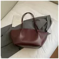 Minimalist deep burgundy tote bag in matte leather for women, shown on white fabric - Purplish Red Without Charms