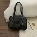 Gros plan du sac en cuir noir brillant avec rivets en cœur et poignées polies - Noir