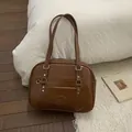 Gros plan d'un sac en simili cuir marron avec boucles cœur sur un tapis doux - Marron