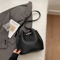 Classic black leather bucket bag with lychee texture and silver lock in urban setting - No Pendant / Black