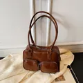 Borsa a spalla retrò marrone lucida con doppie tasche anteriori su un blazer beige - Marrone