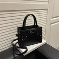Chic black tote bag with matte finish featuring metal studs and buckle strap details - Black