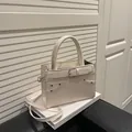 Chic off-white structured handbag with silver buckle and metallic rivet details - White