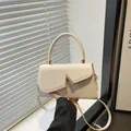 Elegant cream white square handbag with a gold V-shaped buckle and crossbody strap - White