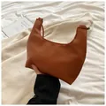 Détail de la texture cuir grainé caramel sur un sac à main en forme de croissant - Marron