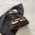 Vintage braune glänzende Schultertasche mit Pattentaschen auf grauem Blazer Hintergrund - Braun