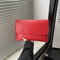 Chique rode envelop clutch tas met matte afwerking in de hand op minimalistisch decor - Rood