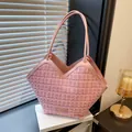 Pink tweed tote bag with gold accents and leather handles on a white book base - Pink