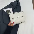Quilted white cosmetic bag with black bow embroidery and zipper closure - Off White
